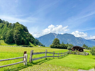 Panorama of the fenced buildings of a mountain village near a ski resort against the background of cloud patterns in the blue sky.