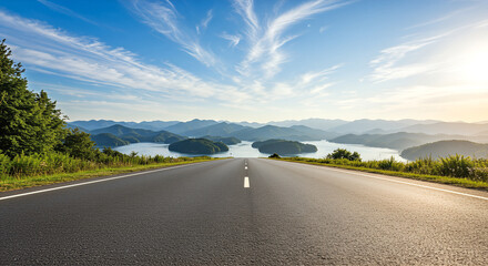 Scenic road leading to a tranquil lake surrounded by mountains under a bright blue sky with wispy clouds.