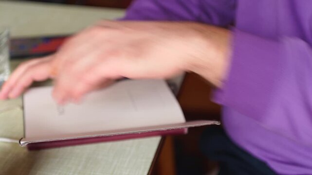 A man's hand turning pages of a notebook closeup