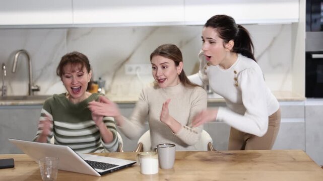 Women are sitting at computer and are immensely happy, exclaim joyfully and are fortunate to receive good news about win
