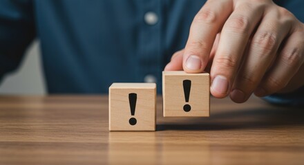Hand places wooden block with exclamation mark on table with another block.