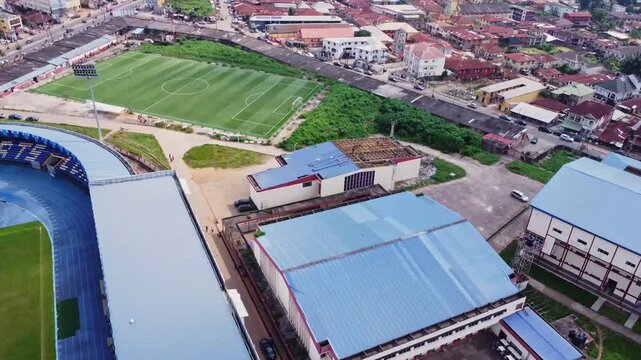 Jib up of a green football field near a sports center in the city of Ibadan, Nigeria on a sunny day