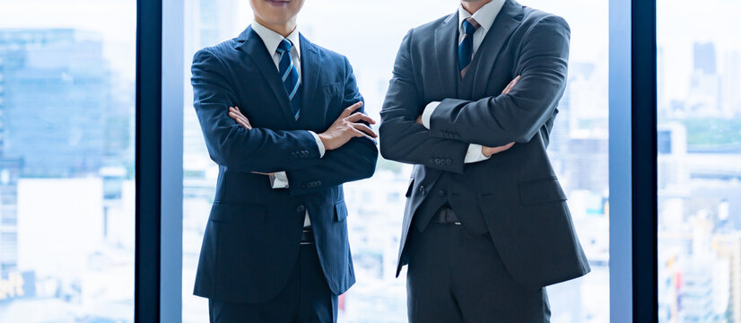 オフィスで並ぶスーツ姿のビジネスマン・ビジネスパートナーとして信頼関係を築く男性たち