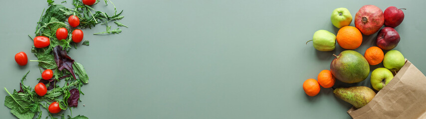 Fresh produce arrangement with tomatoes, greens, and a variety of fruits on a neutral background