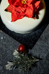 A beautifully crafted dessert showcases a striking flower decoration, enhanced by twinkling lights and festive greens, creating an inviting holiday atmosphere.