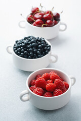 Bowls of raspberries, blueberries and cherries for fruit trio, diet or nutrition concept