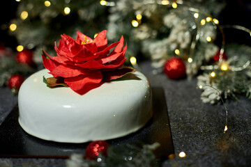A beautifully crafted dessert showcases a striking flower decoration, enhanced by twinkling lights and festive greens, creating an inviting holiday atmosphere.