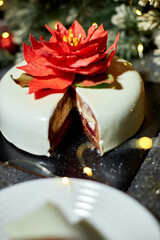 A beautifully arranged plate holds a slice of decadent layered cake, showcasing red velvet and cream cheese layers, surrounded by twinkling lights and holiday decor.