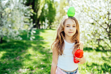 Easter egg hunt. Girl child Wearing Bunny Ears Running To Pick Up Egg In Garden. Easter tradition....