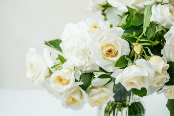 Closeup of white roses bouquet with green leaves in soft natural light