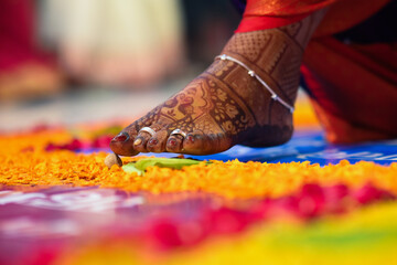 Leg of bride touch the stone in indian wedding ceremony. seven steps wedding ceremony. flowers petals and leaf. colorful steps. close up feet