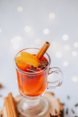 Warm winter drink with orange slices cinnamon stick and star anise on a wooden slice with soft lights