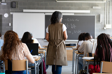 Teacher walking in classroom while students are studying science