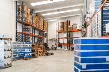 Industrial warehouse interior with racking storing pallets, shipping containers, and packaging...