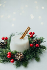 Creamy winter drink with cinnamon stick and festive evergreen decoration © reddish