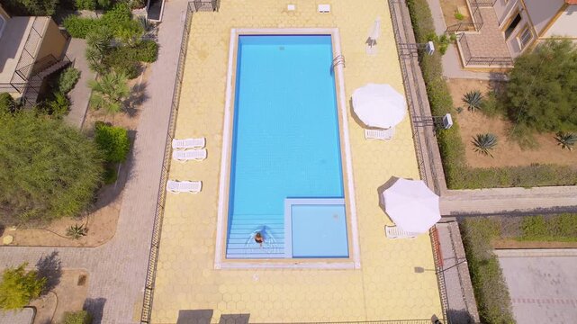 Woman Entering Swimming Pool on Sunny Day, Aerial Drone View