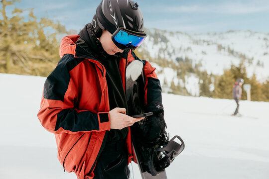 Snowboarder checking phone at ski winter resort