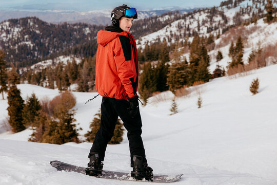 Young man snowboarding on mountain slope in winter