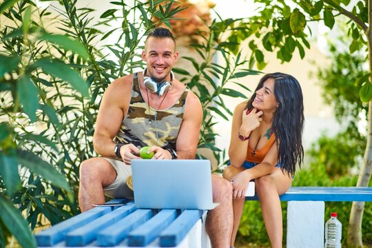happy man holding apple, sitting on bench with laptop and woman