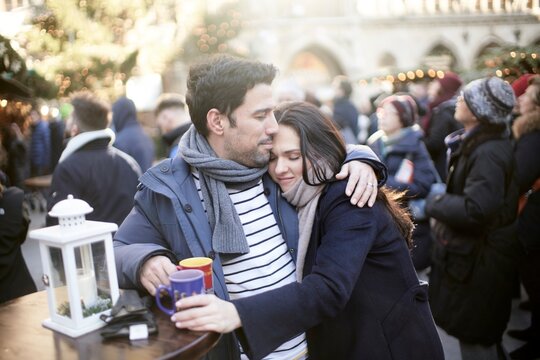 couple at christmas market, content husband comforting bugged wife