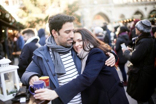 couple with hot spiced wine punch cups at christmas market outside