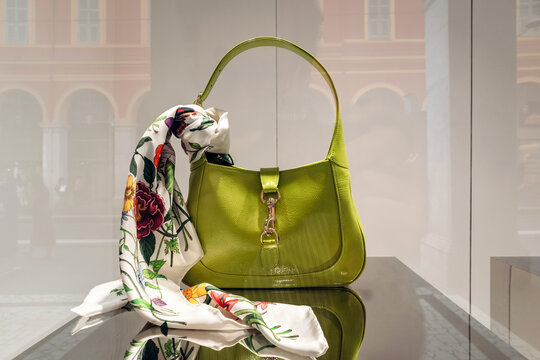 Nice, France - June 14, 2025: Green Gucci Jackie handbag with floral silk scarf displayed in the window of Galeries Lafayette