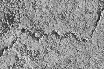 Uneven cracked peeling concrete floor texture background. Rough and grunge surface in the sun. Old dirty background.