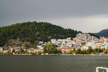 Kastoria, Greece. Panoramic view of Kastoria city by the lake on a cloudy autumn day, with reflections on the calm water and traditional houses on the hill.