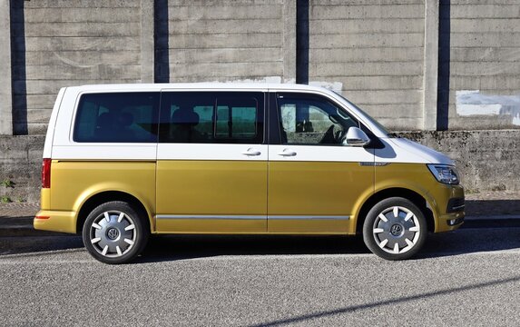 Udine, Italy. October 13, 2025. Side view of Volkswagen Multivan T7 at the roadside with grunge concrete wall on behind.