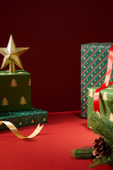 Vertical Christmas photo with stacked gift boxes, golden star ornament, and pine branches. Cozy warm tone ideal for Christmas card or winter sale banner.