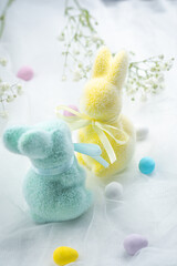 Colorful plush bunnies with pastel eggs and flowers set on a soft background