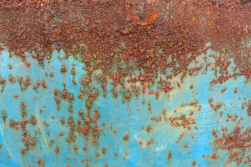 Close-up of rusty corrosion forming on an old blue painted metal surface showing decay and texture details.
