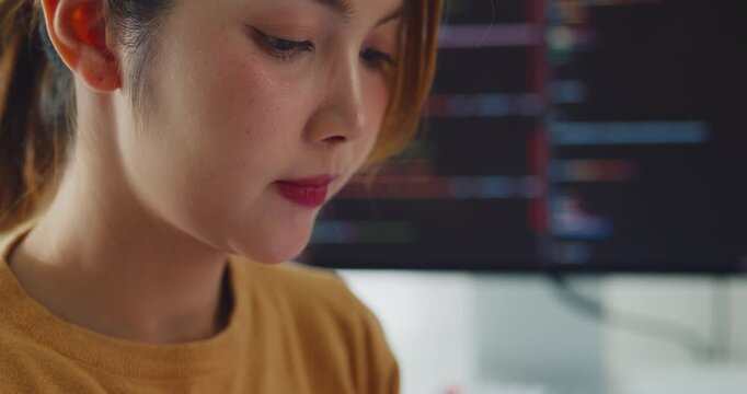 Closeup young Asia female freelance write code on tablet while work prompt AI IT app smart program nomad, video game, terminal coding, user interface, data center on desktop computer at home office.