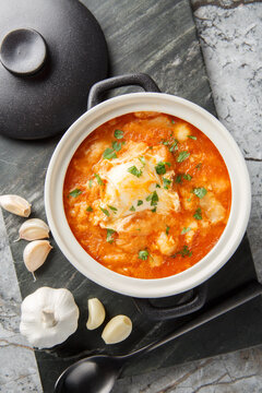 Zurrukutuna is a traditional Basque soup whose main ingredients are cod, bread, garlic, ​​pepper and egg closeup in the saucepan on the table. Vertical top view from above
