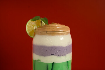 Fresh and vibrant drink with gradient green and purple tones, kiwi slices, and red studio background.
