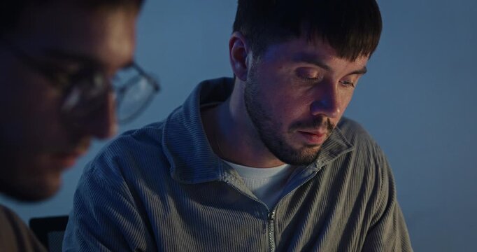 Closeup team adult male engineer collaborate on robotic hand project use AI code solutions machine learn at tech workspace night. Artificial intelligence interface collaboration prototype development.