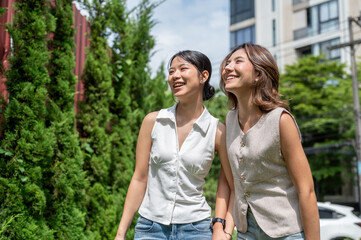 Obraz premium Pretty asian woman friends holding hands standing or walking outdoor together in hot summer sunlight