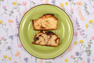 Two slices of marbled sweet bread, one with a chocolate swirl, are placed on a green plate on a light floral tablecloth