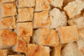 A close-up, full-frame shot of many small, square pieces of light-crusted bread, suitable for croutons, filling the entire image