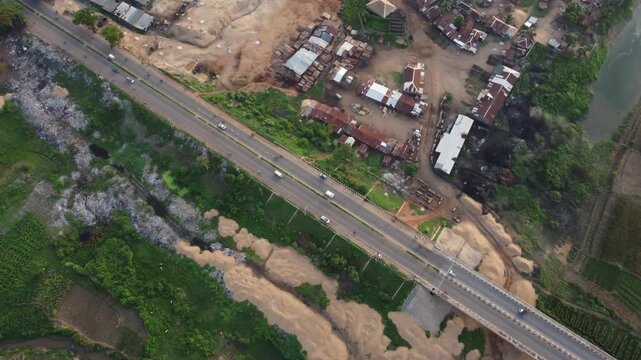 Aerial view of the Benue River and the adjacent road, with vehicles moving along, nestled in the vibrant landscape, Makurdi, Benue, Nigeria.