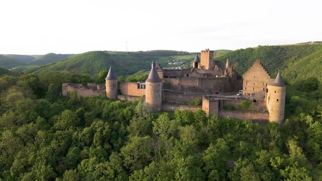 bourscheid castle ch&acirc;teau de surrounded by green cover hills farms visitor cars park compound road passing beside under to left right circling drone shot luxembourg 