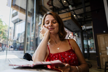 Relaxed woman reading a menu in a bright urban cafe