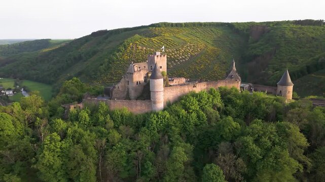 bourscheid castle ch&acirc;teau de surrounded by green cover hills farms river valley beautiful homes under sunny skies to left right circling drone luxembourg 