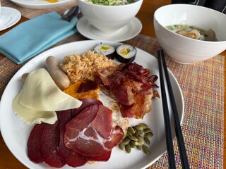 Traditional Vietnamese breakfast served on a plate, featuring savory bacon, cured meat, cheese, dried squid, and aromatic national sou