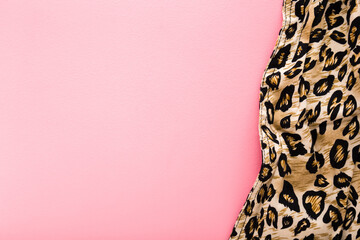Dark black yellow soft wavy leopard spot pattern fabric on light pink table background. Pastel...