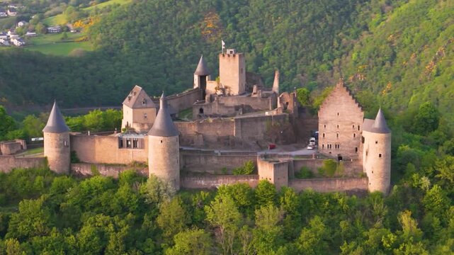bourscheid castle ch&acirc;teau de green cover hills walls towers flags visitor vehicles beautiful town behind to left right close pans drone luxembourg panning 