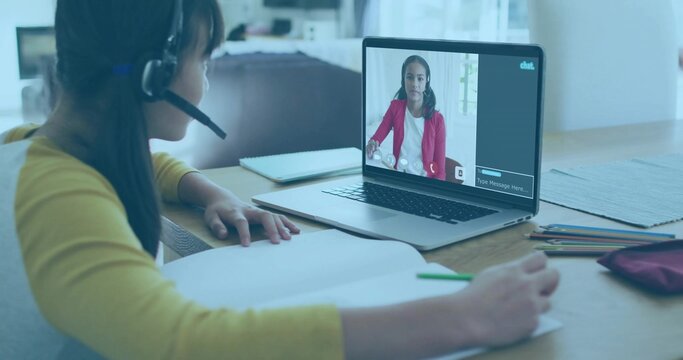 Writing student wearing yellow top and headset at home at wooden table with laptop, copy space