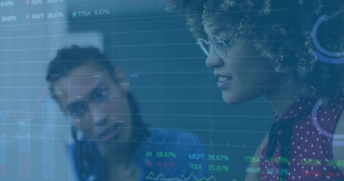 Analyzing female analyst studying stock charts on translucent panel in office, with ticker symbols