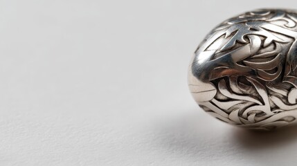 Closeup of a shiny chrome orb with intricate ribbonlike engravings on a glossy white surface, low angle, detailed metal textures, modern and elegant aesthetic, copy space on left
