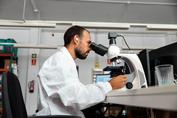 Scientist using microscope and tablet in modern laboratory workspace